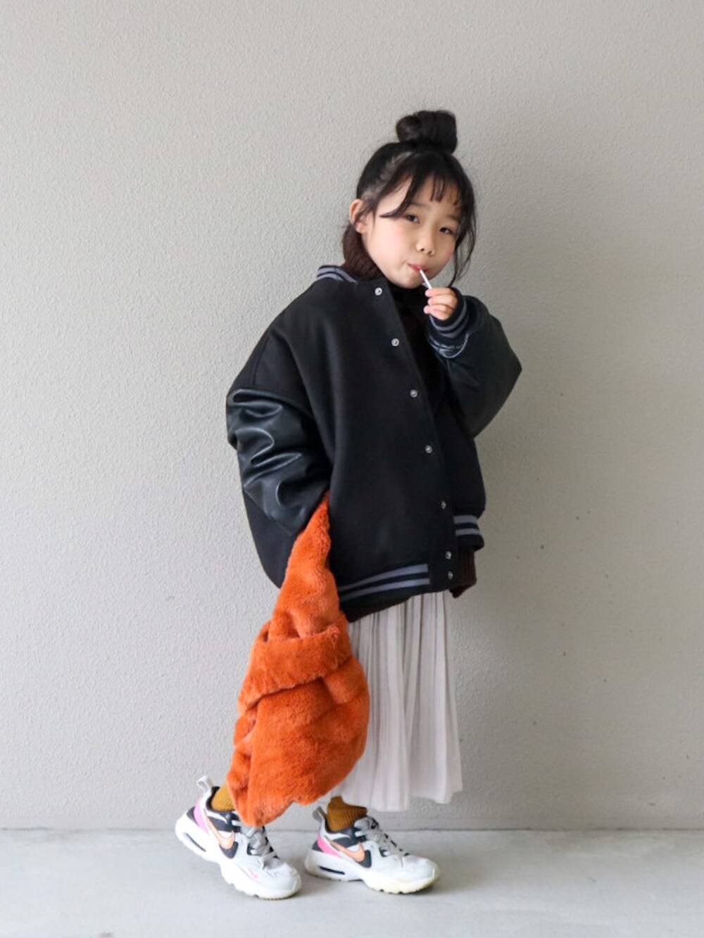 ブラック系のスタジャン、ブラウン系のニット/セーター、ホワイト系のスカートを着用したキッズの冬コーディネートの2枚目の写真