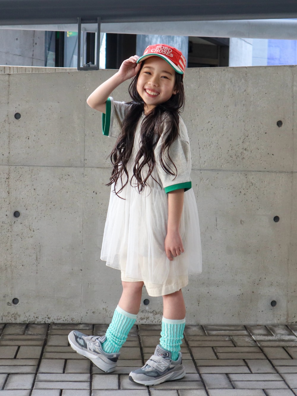 ホワイト系のチュニック、グリーン系のTシャツ/カットソー、ホワイト系のデニムパンツを着用したキッズの春コーディネートの2枚目の写真