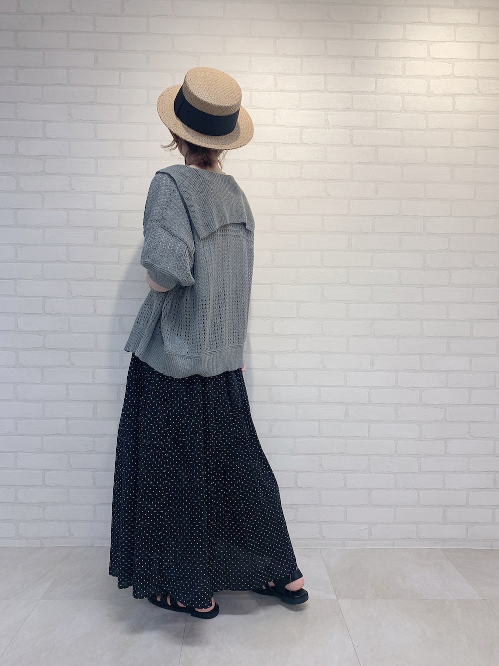 ブラック系のスカート、グレー系のニット/セーター、ホワイト系のTシャツ/カットソーを着用したレディースの春コーディネートの4枚目の写真