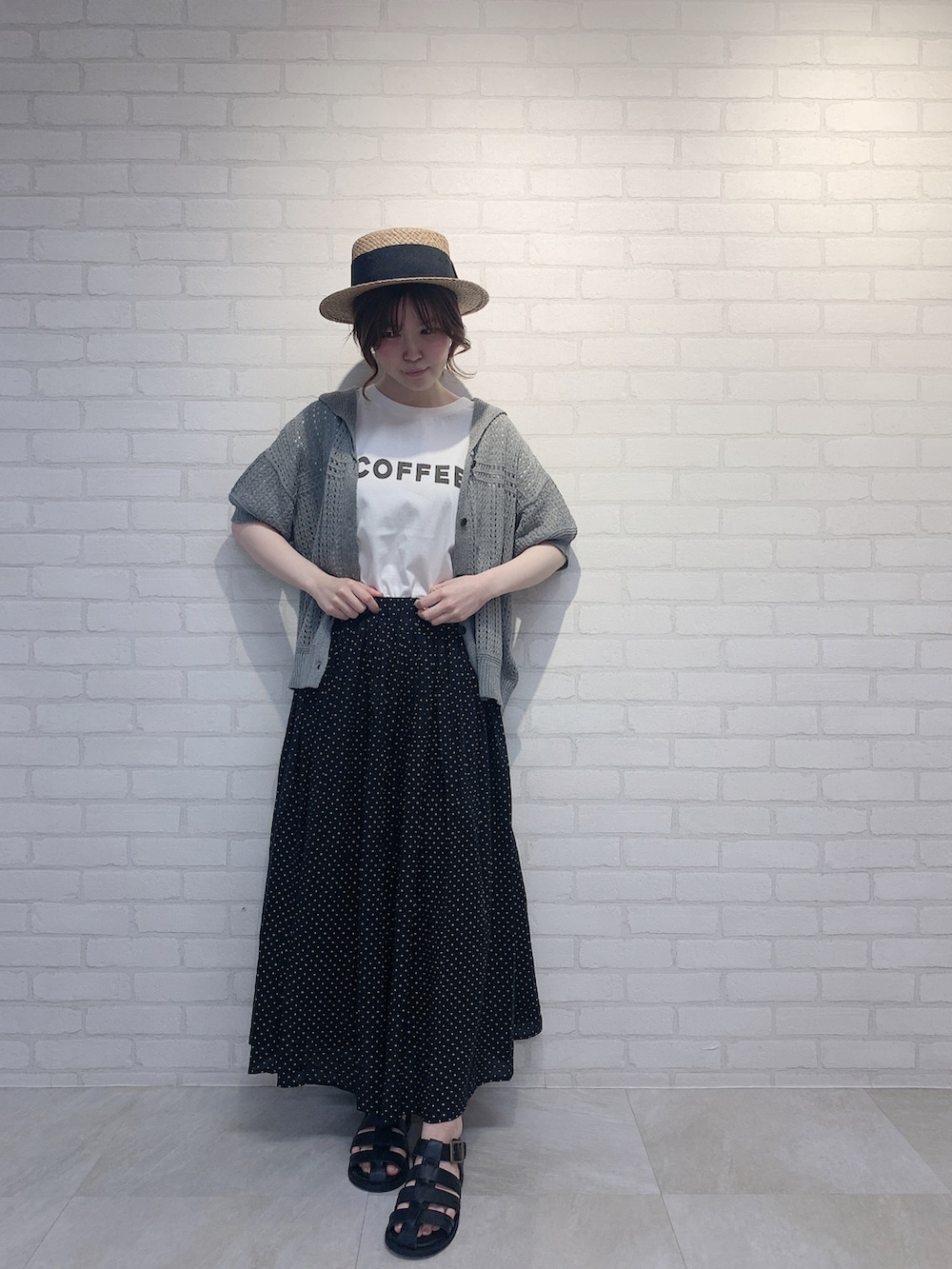 ブラック系のスカート、グレー系のニット/セーター、ホワイト系のTシャツ/カットソーを着用したレディースの春コーディネートの2枚目の写真