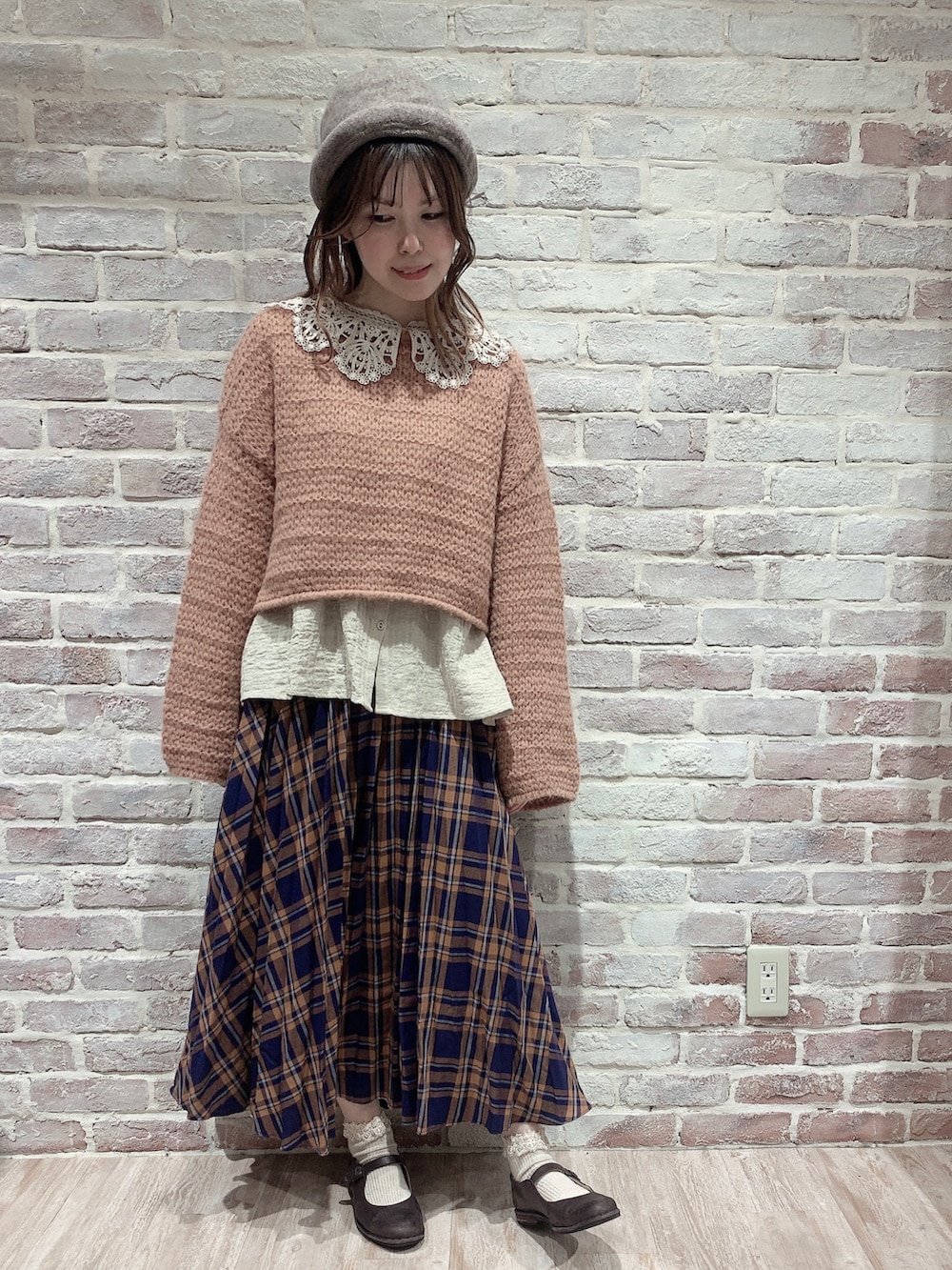 オレンジ系のニット/セーター、ベージュ系のシャツ/ブラウス、ブルー系のスカートを着用したレディースの秋コーディネートの2枚目の写真