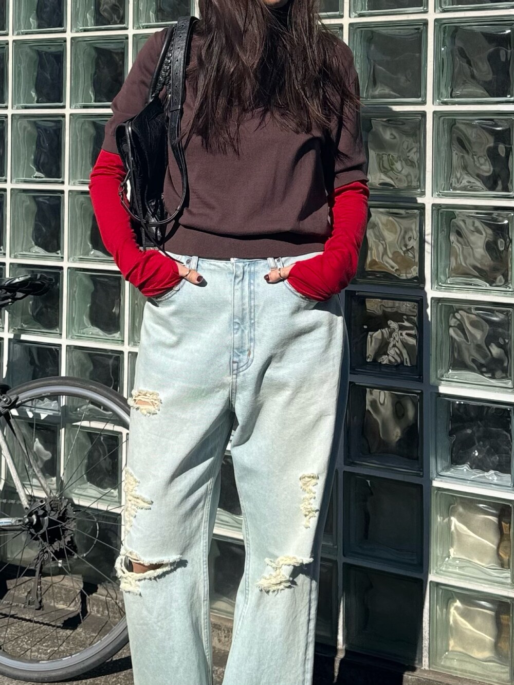 ブラウン系のニット/セーター、レッド系のTシャツ/カットソー、ブルー系のデニムパンツを着用したレディースの冬コーディネートの2枚目の写真