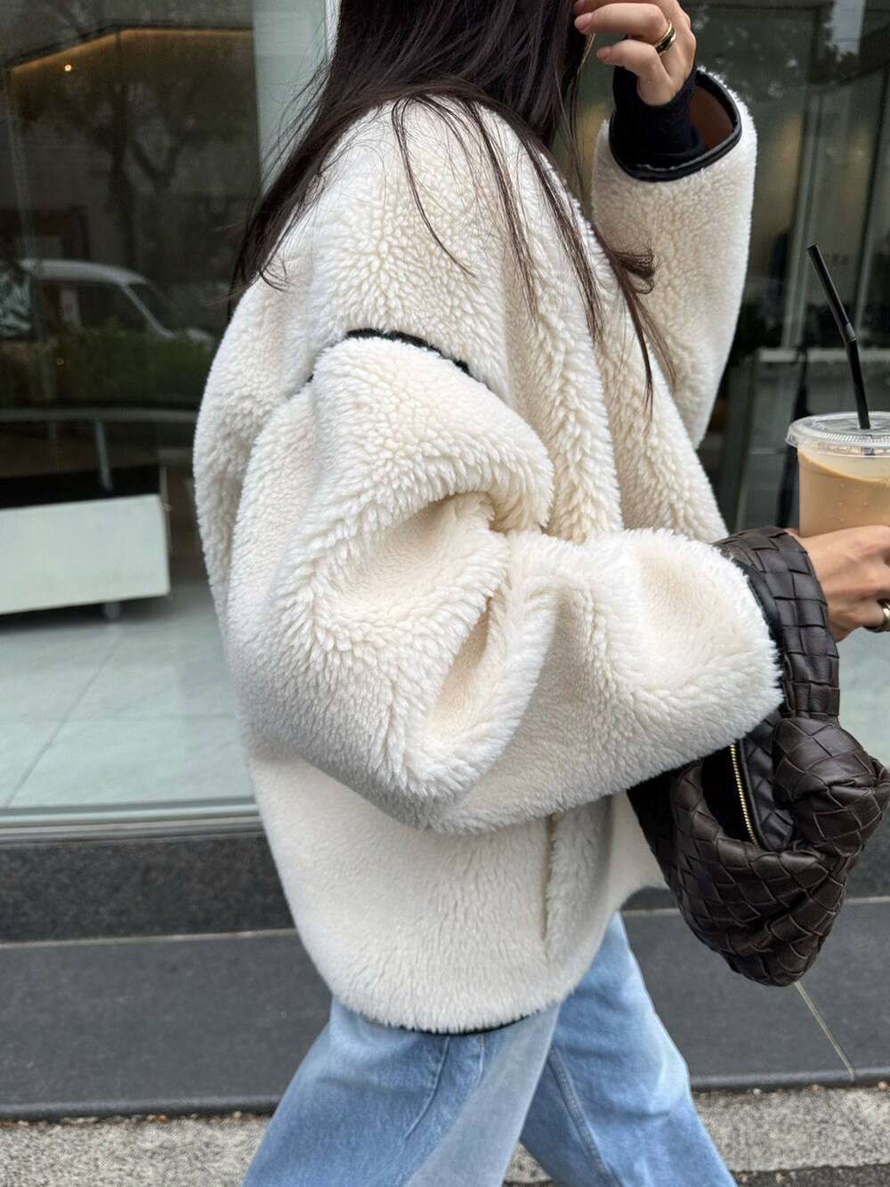 ホワイト系のブルゾン、ブラウン系のバッグ、ブルー系のパンツを着用したレディースの秋コーディネートの2枚目の写真