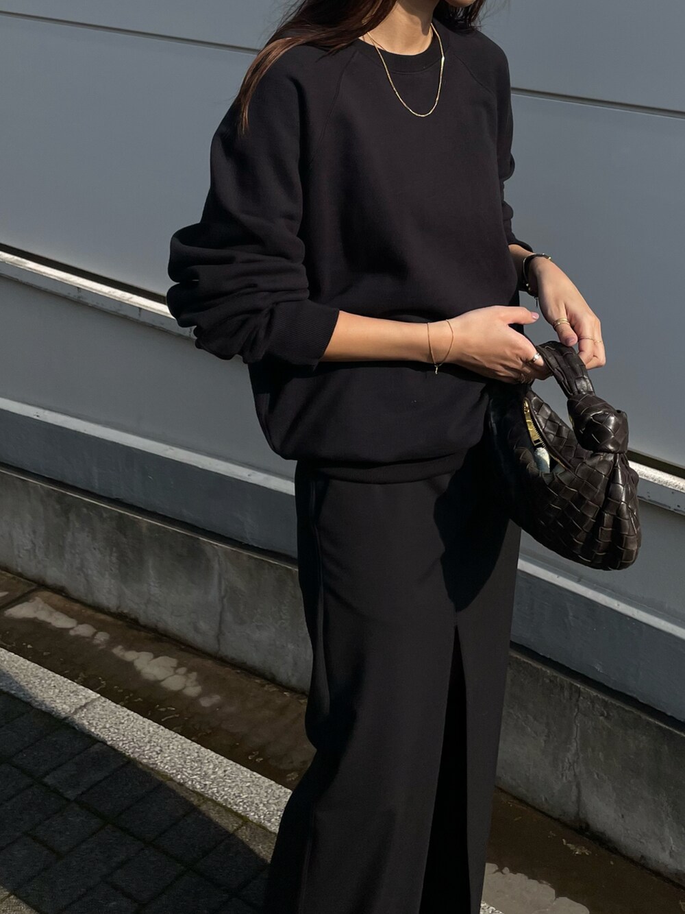 ブラック系のスウェット、ブラウン系のバッグ、ブラック系のシューズを着用したレディースの春コーディネートの2枚目の写真