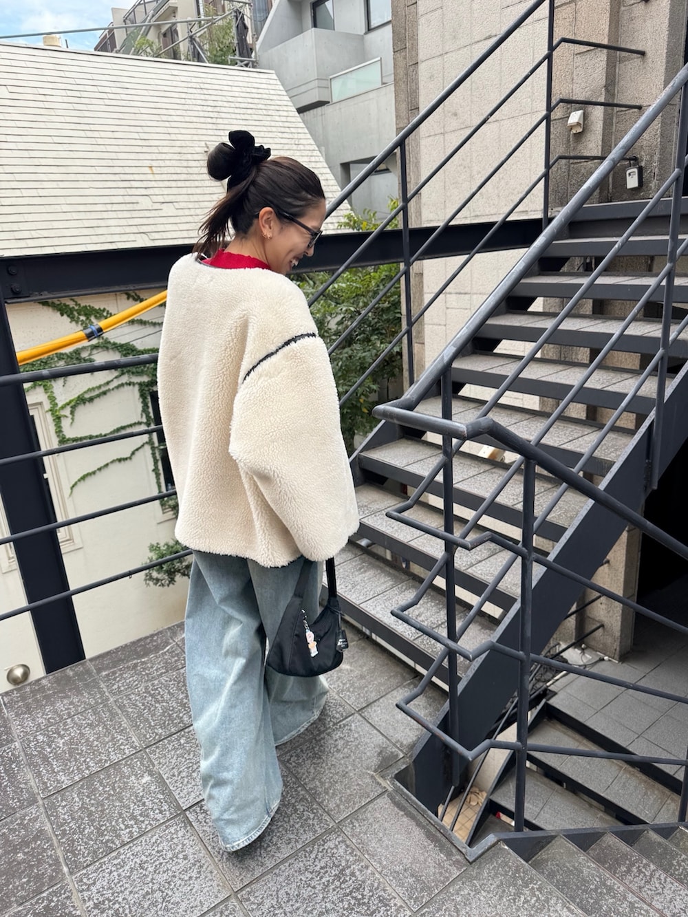 ホワイト系のダウンジャケット/コート、ブルー系のデニムパンツ、ブラック系のバッグを着用したレディースの秋コーディネートの2枚目の写真