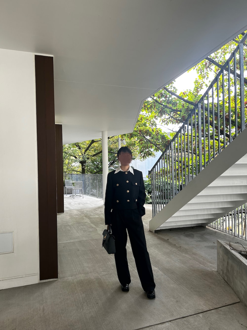 ブラック系のノーカラージャケット、ブラック系のハンドバッグ、ブラック系のブーツを着用したレディースの冬コーディネートの2枚目の写真