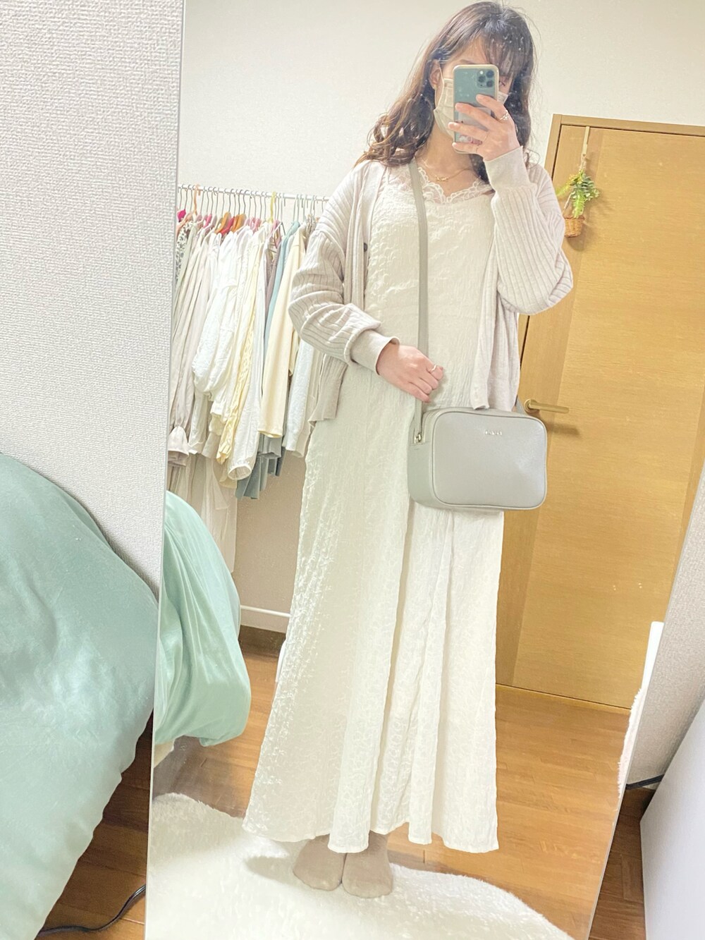 ホワイト系のワンピース、ベージュ系のトップス、ブラウン系の財布を着用したレディースの春コーディネートの2枚目の写真