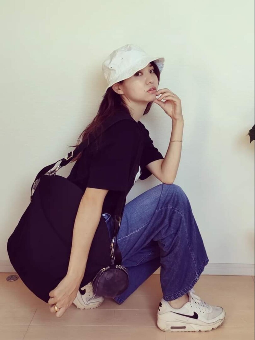 ブラック系のTシャツ/カットソー、ブルー系のデニムパンツ、ブラック系のバッグを着用したレディースの秋コーディネートの4枚目の写真