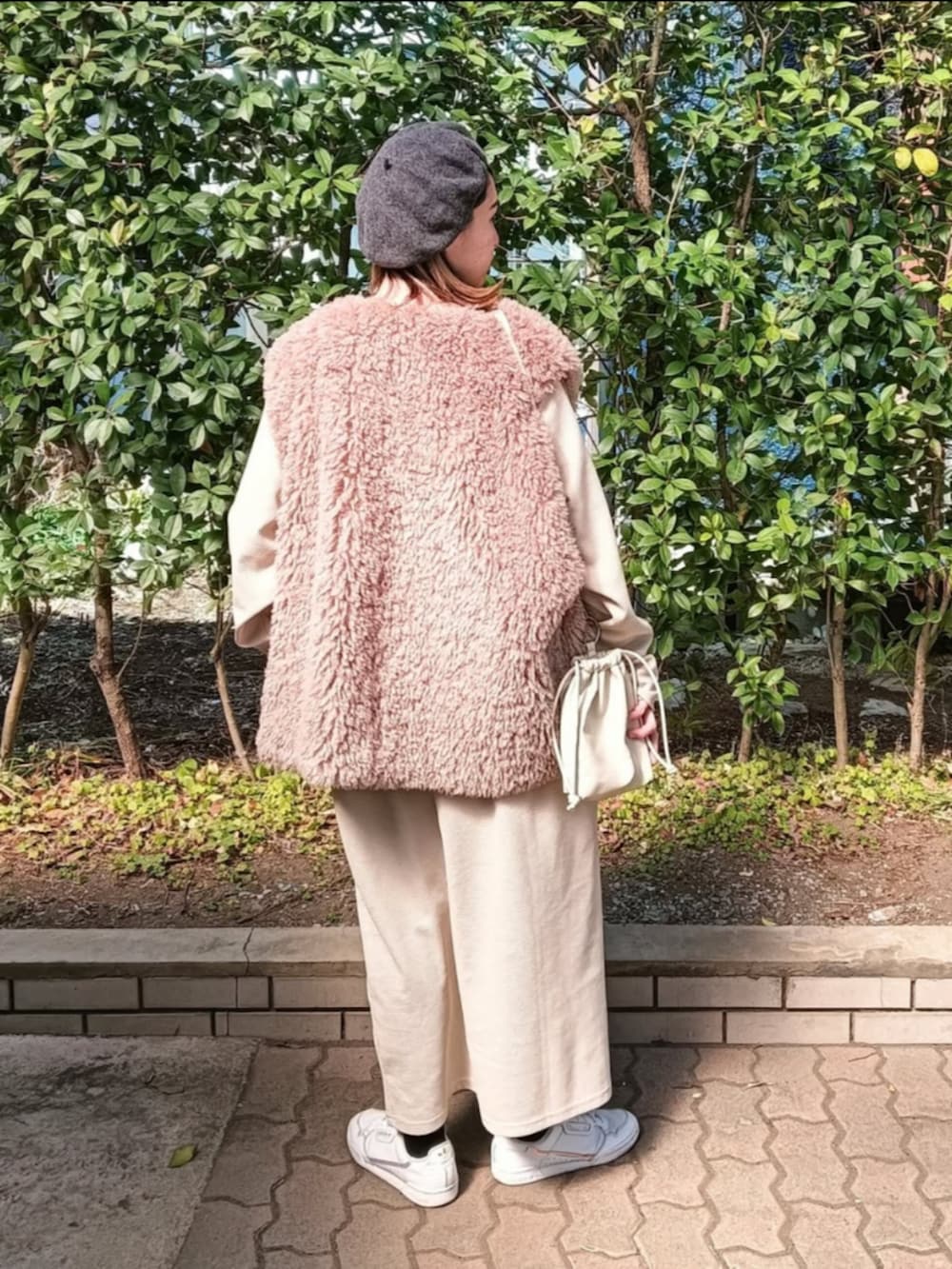 ベージュ系のワンピース、ブラック系のベスト、ホワイト系のショルダーバッグを着用したレディースの春コーディネートの3枚目の写真