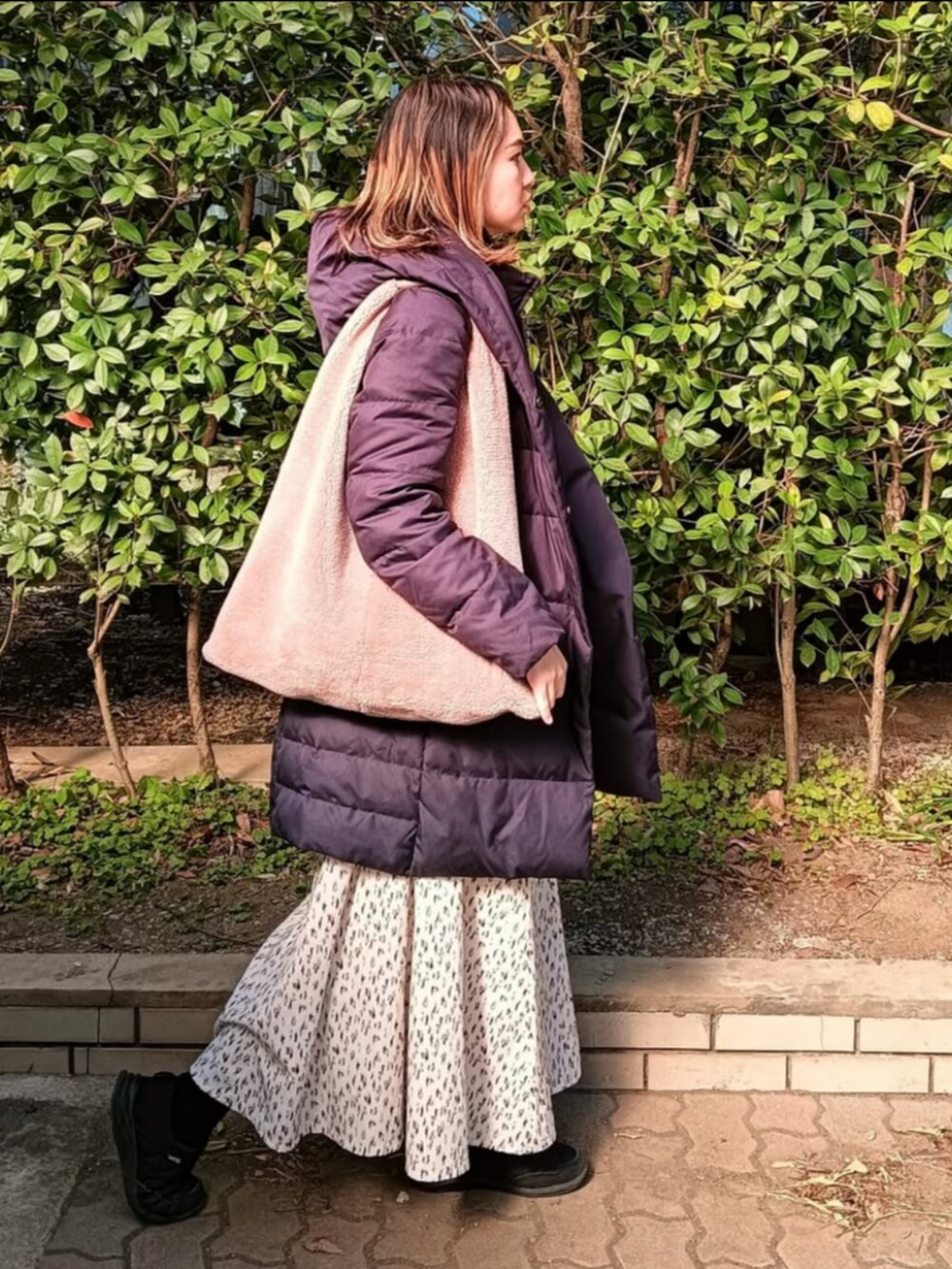 ベージュ系のニット/セーター、ブルー系のダウンジャケット/コート、ベージュ系のショルダーバッグを着用したレディースの冬コーディネートの2枚目の写真