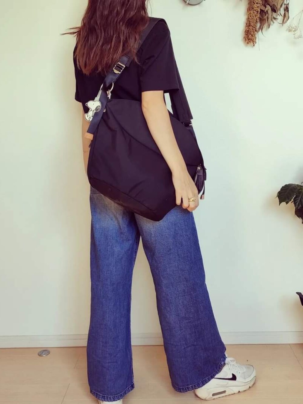 ブラック系のTシャツ/カットソー、ブルー系のデニムパンツ、ブラック系のバッグを着用したレディースの秋コーディネートの2枚目の写真