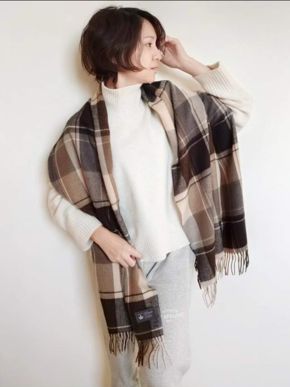 ホワイト系のニット/セーター、グレー系のスウェットパンツ、ベージュ系のストール/ショールを着用したレディースの冬コーディネートの2枚目の写真