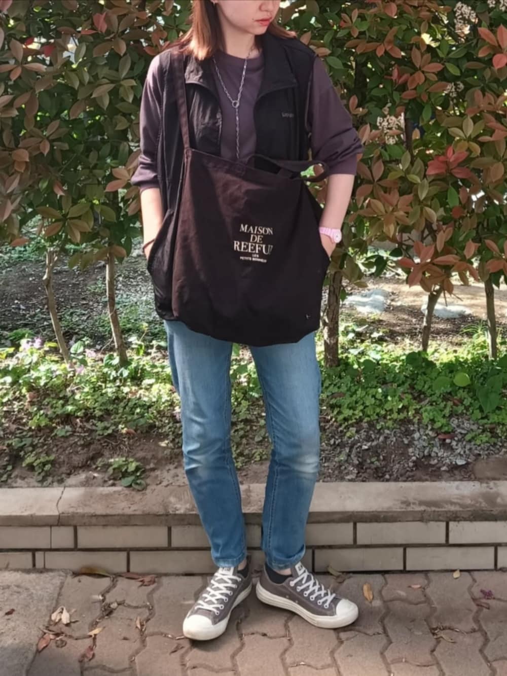 ブラック系のベスト、グレー系のTシャツ/カットソー、ブラック系のトートバッグを着用したレディースの春コーディネートの2枚目の写真