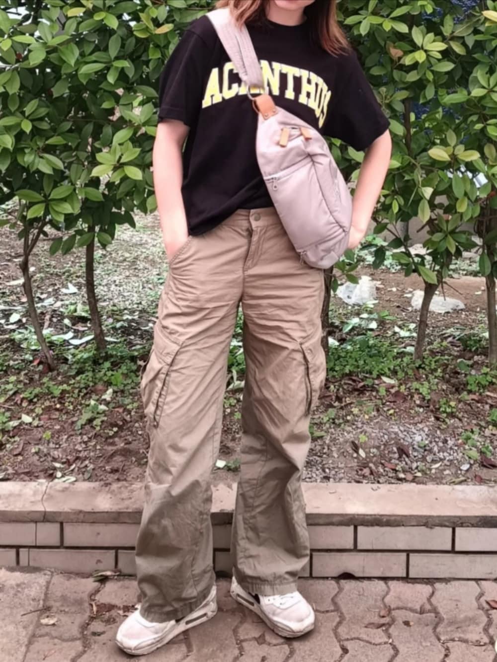 ブラック系のTシャツ/カットソー、ホワイト系のボディバッグ/ウエストポーチ、グリーン系のカーゴパンツを着用したレディースの春コーディネートの2枚目の写真