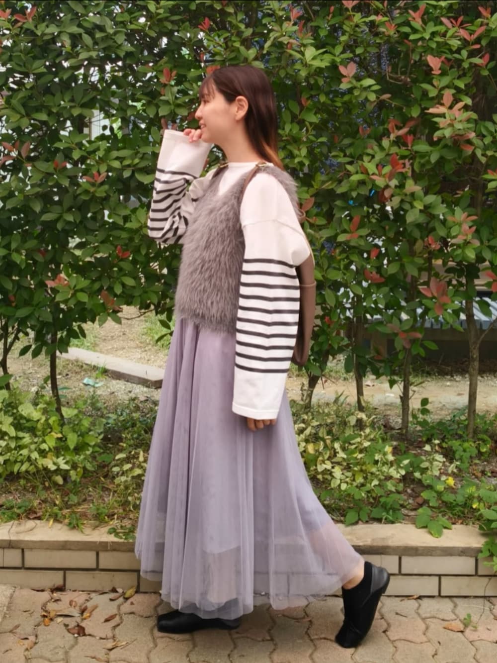 グレー系のベスト、ホワイト系のTシャツ/カットソー、グレー系のスカートを着用したレディースの秋コーディネートの2枚目の写真