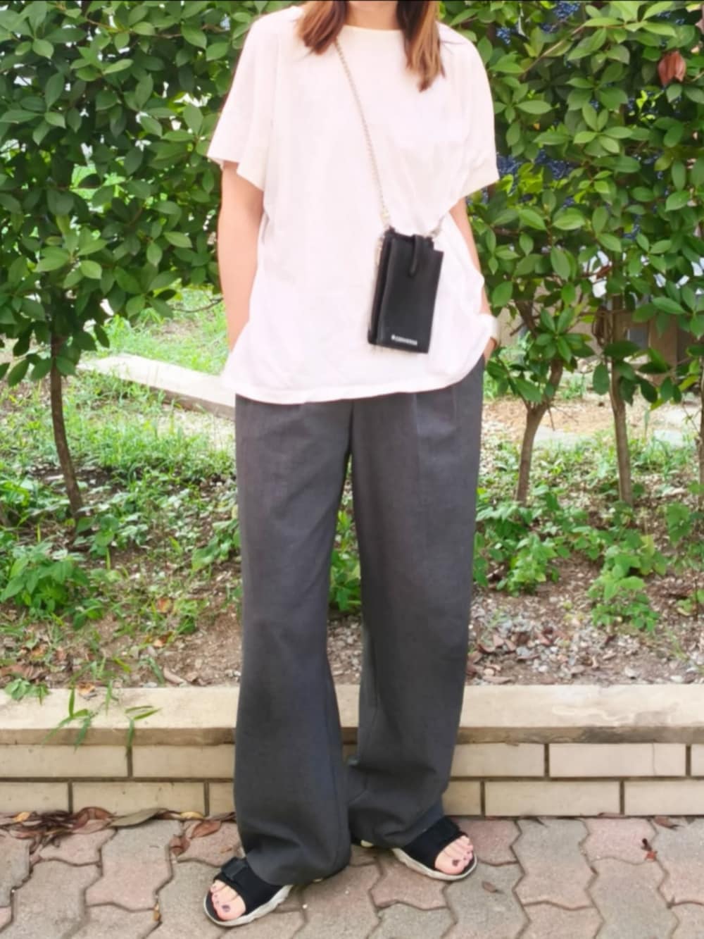 ホワイト系のTシャツ/カットソー、ブラック系のショルダーバッグ、グレー系のパンツを着用したレディースの秋コーディネートの2枚目の写真