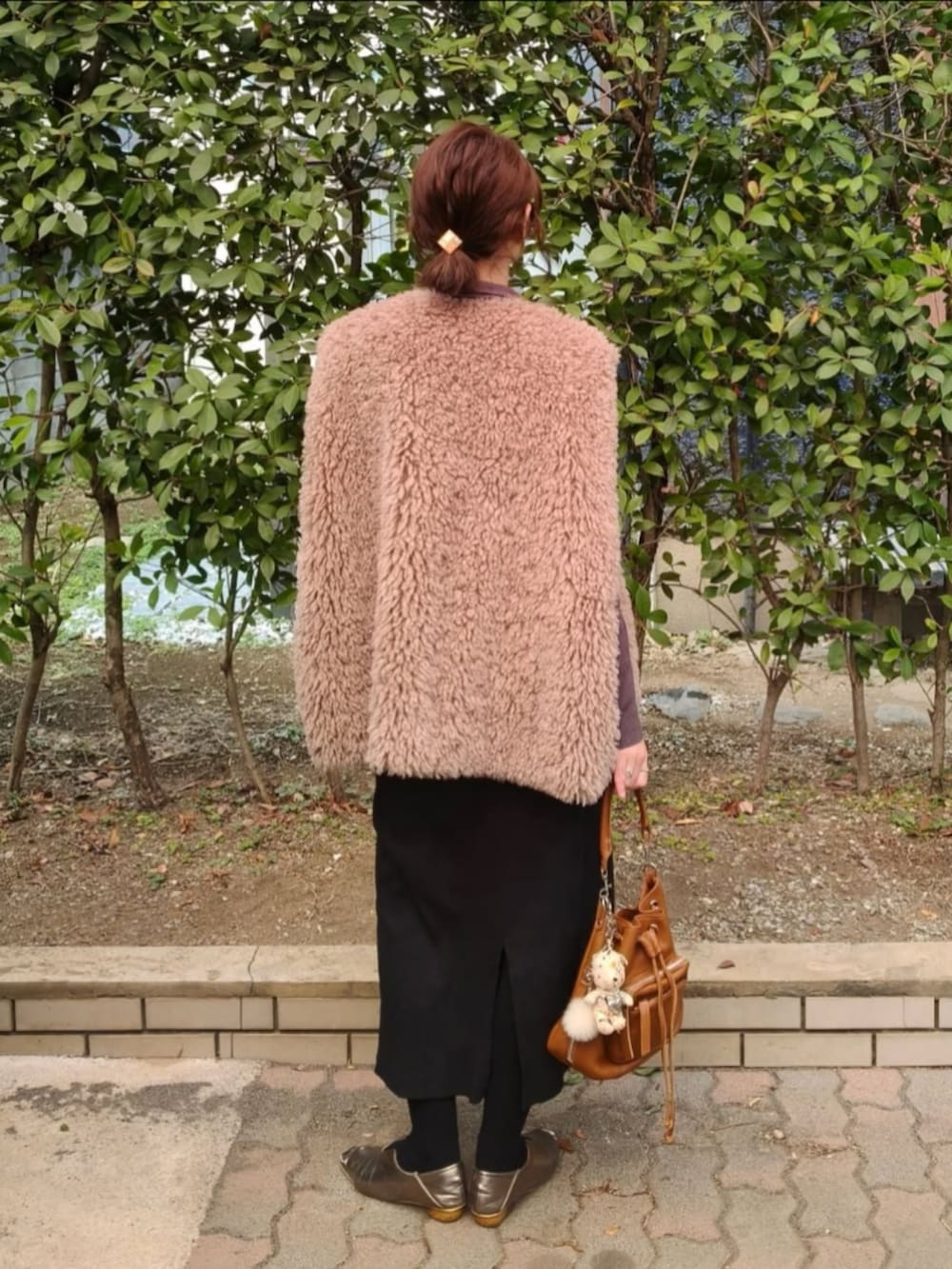 グレー系のニット/セーター、ブラック系のベスト、ブラウン系のショルダーバッグを着用したレディースの春コーディネートの3枚目の写真