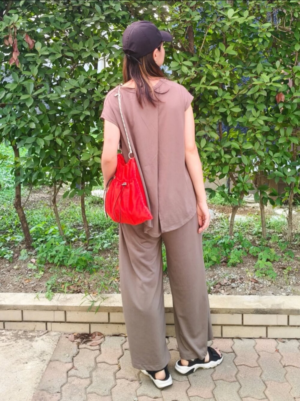 ブラウン系のTシャツ/カットソー、オレンジ系のショルダーバッグ、ブラック系のサンダルを着用したレディースの夏コーディネートの3枚目の写真