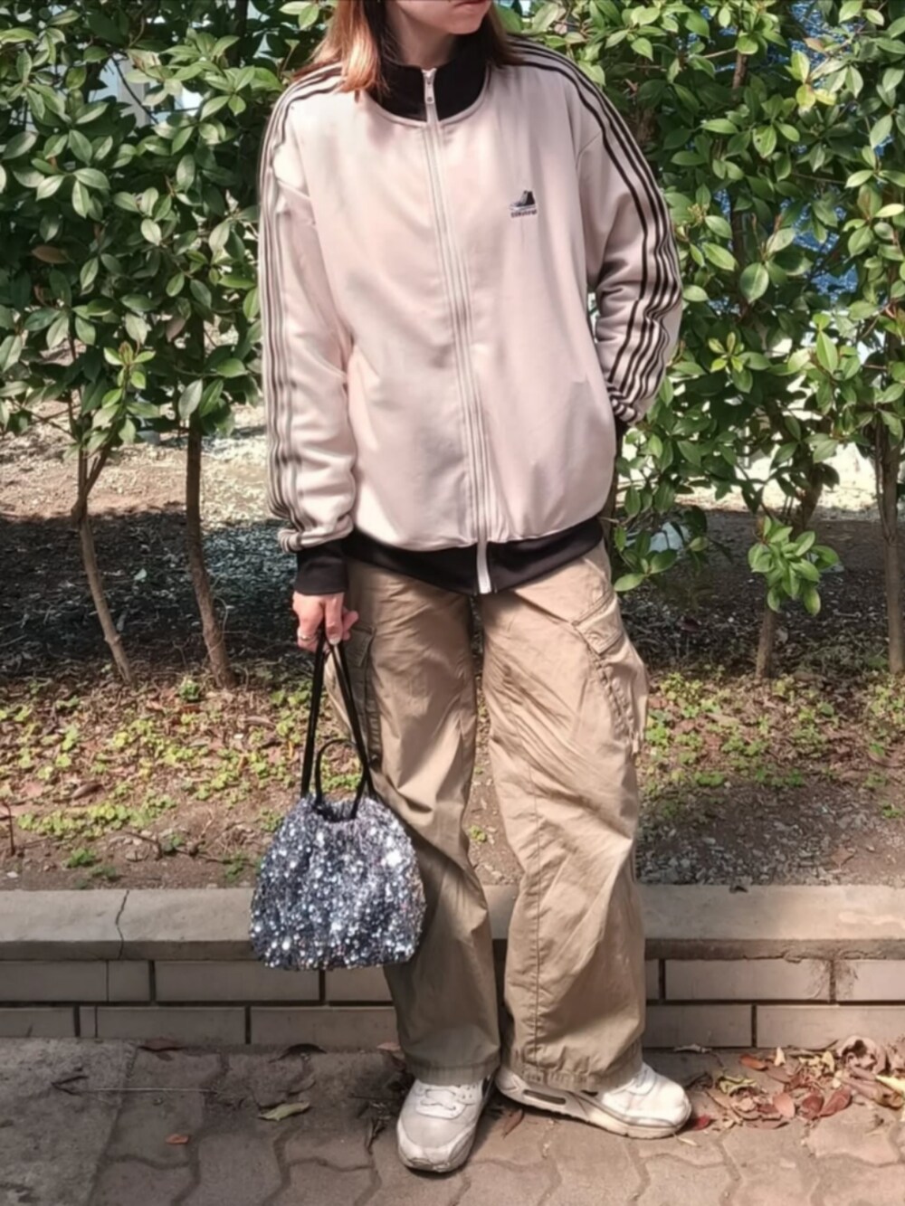 ベージュ系のジャージ、グリーン系のカーゴパンツ、シルバー系のショルダーバッグを着用したレディースの春コーディネートの2枚目の写真