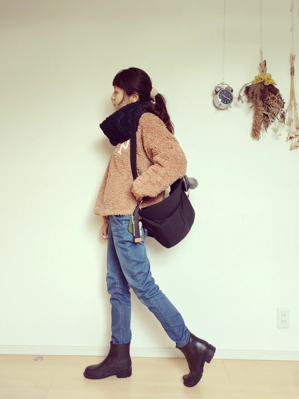 ブラック系のバッグ、ブラック系のレインシューズ、ブルー系のデニムパンツを着用したレディースの秋コーディネートの2枚目の写真