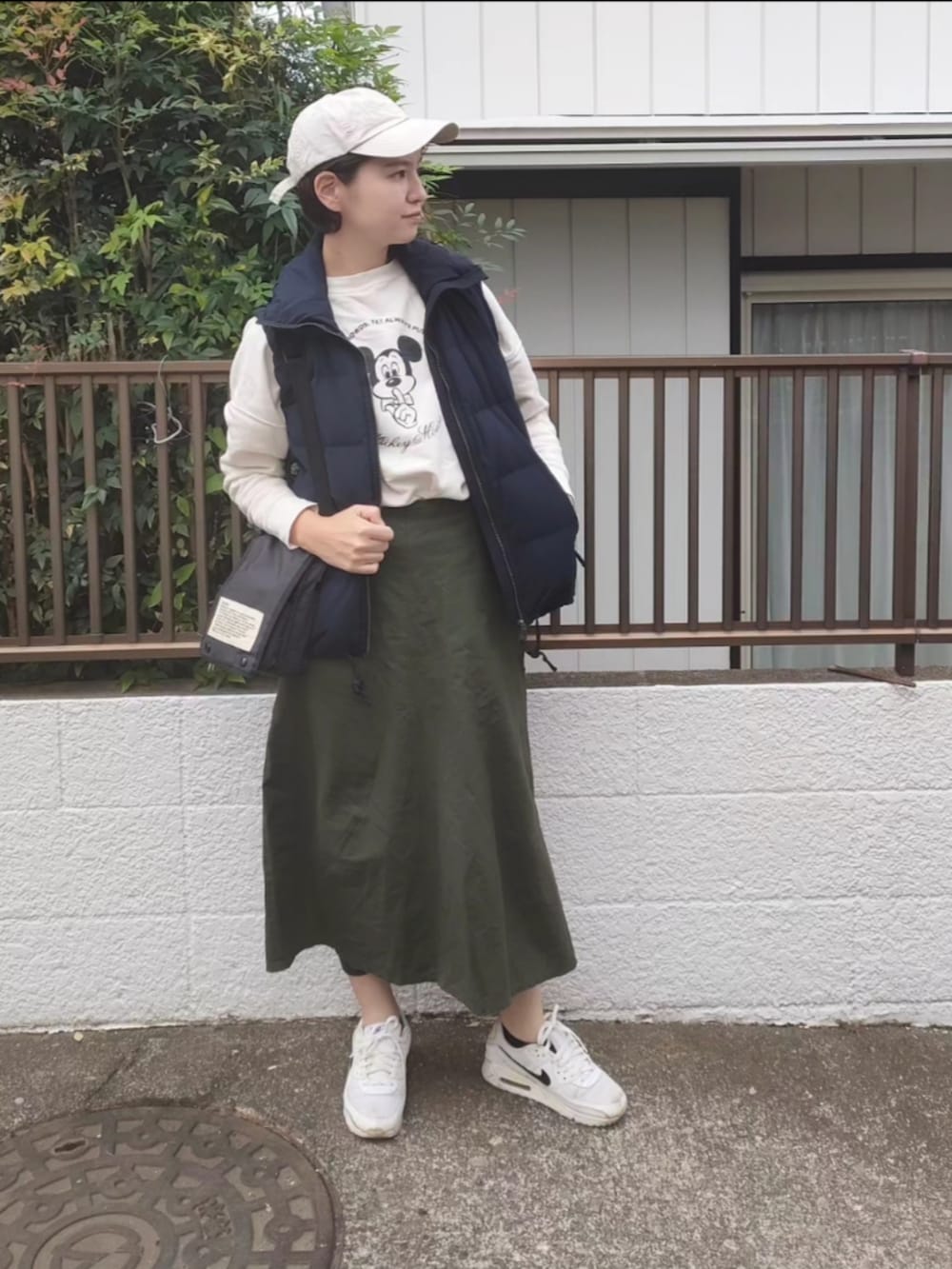 ブラック系のダウンベスト、ホワイト系のスウェット、ブラック系のショルダーバッグを着用したレディースの秋コーディネートの3枚目の写真