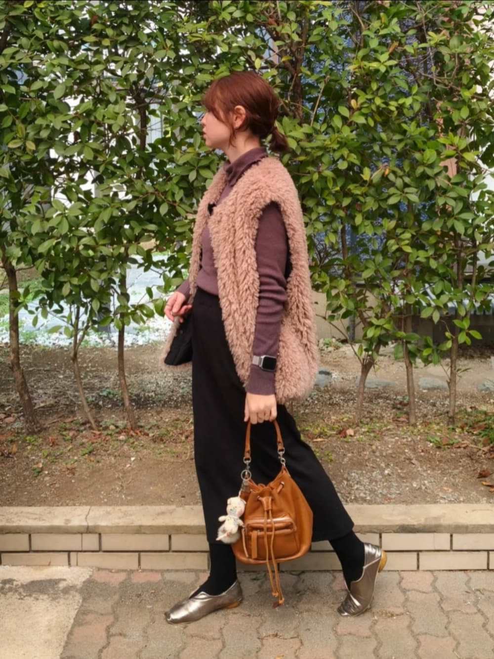 グレー系のニット/セーター、ブラック系のベスト、ブラウン系のショルダーバッグを着用したレディースの春コーディネートの2枚目の写真