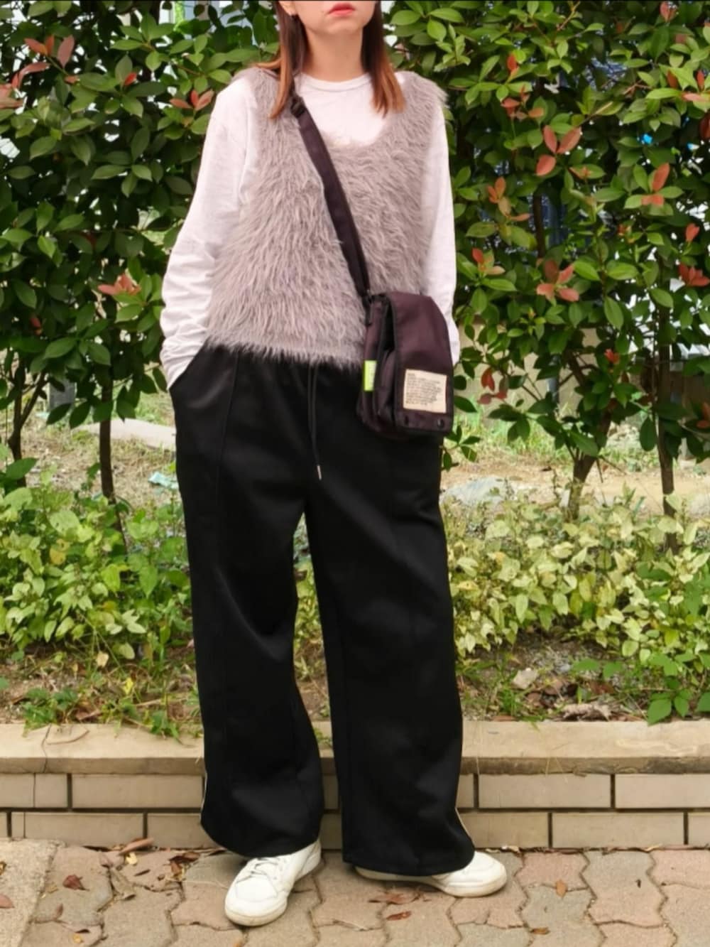 グレー系のTシャツ/カットソー、グレー系のベスト、ブラック系のショルダーバッグを着用したレディースの秋コーディネートの2枚目の写真