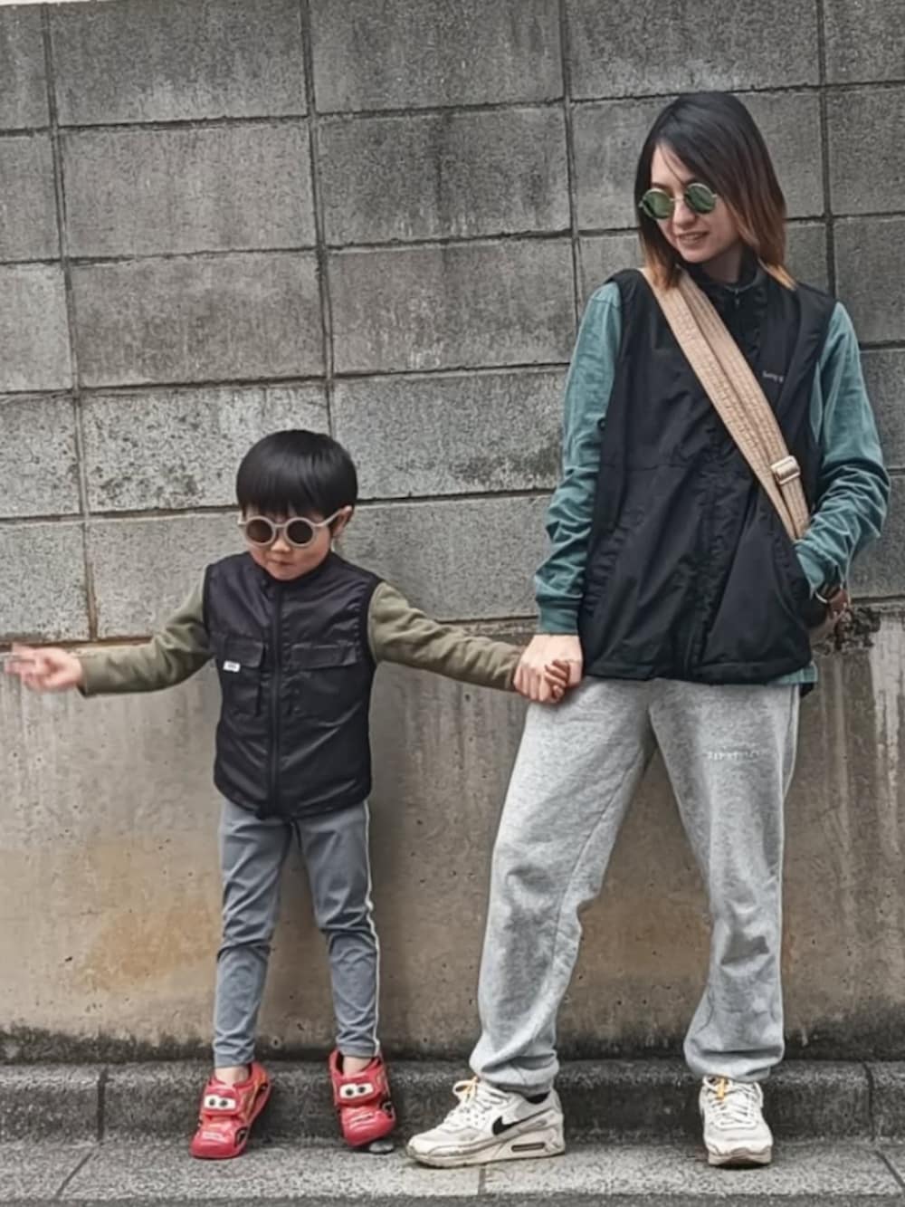 ブラック系のベスト、グリーン系のTシャツ/カットソー、ベージュ系のショルダーバッグを着用したレディースの秋コーディネートの2枚目の写真