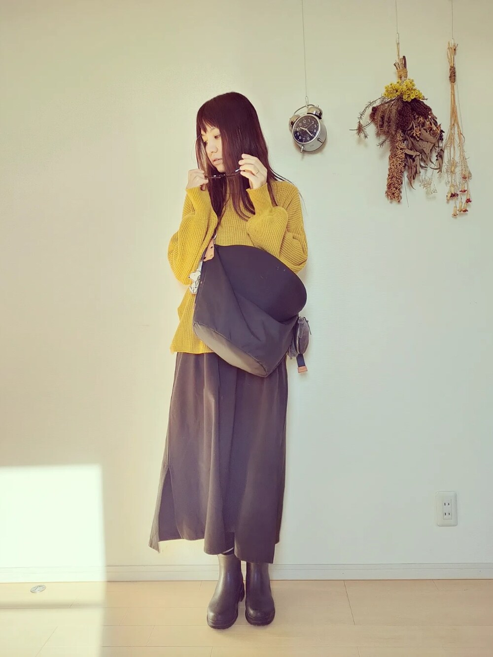 イエロー系のニット/セーター、ブラック系のバッグ、ブラック系のオールインワン・サロペットを着用したレディースの秋コーディネートの4枚目の写真