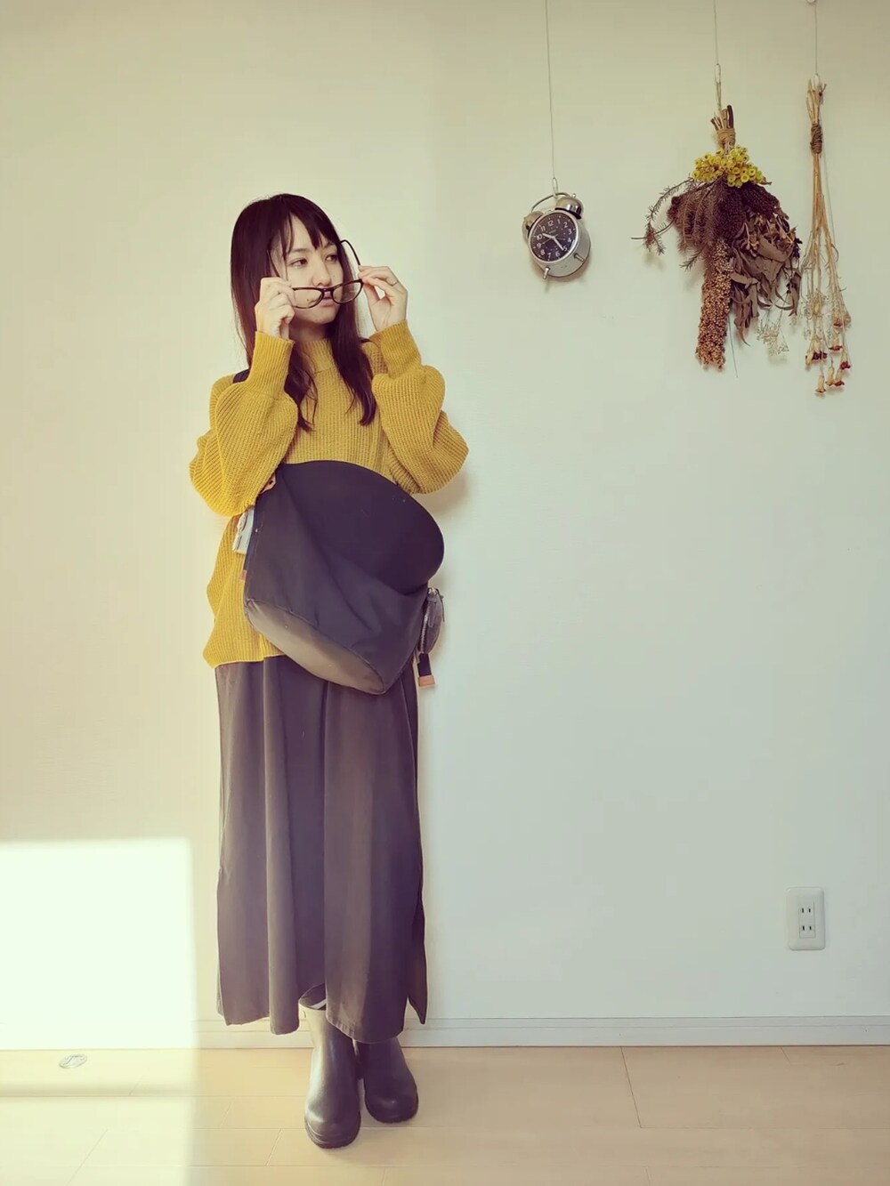 イエロー系のニット/セーター、ブラック系のバッグ、ブラック系のオールインワン・サロペットを着用したレディースの秋コーディネートの2枚目の写真