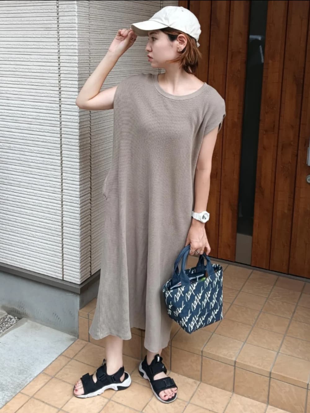ブラウン系のワンピース、ブルー系のトートバッグ、ブラック系のサンダルを着用したレディースの夏コーディネートの2枚目の写真