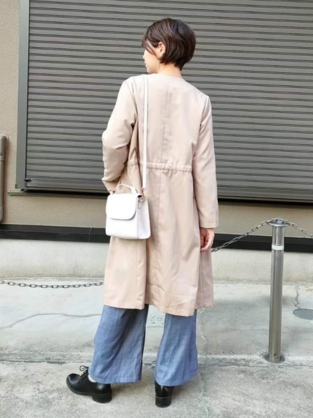 ベージュ系のノーカラーコート、ホワイト系のショルダーバッグ、ブラック系のドレスシューズを着用したレディースの冬コーディネートの3枚目の写真
