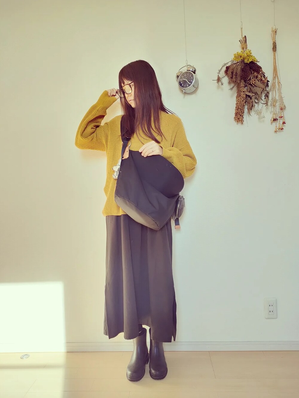 イエロー系のニット/セーター、ブラック系のバッグ、ブラック系のオールインワン・サロペットを着用したレディースの秋コーディネートの3枚目の写真