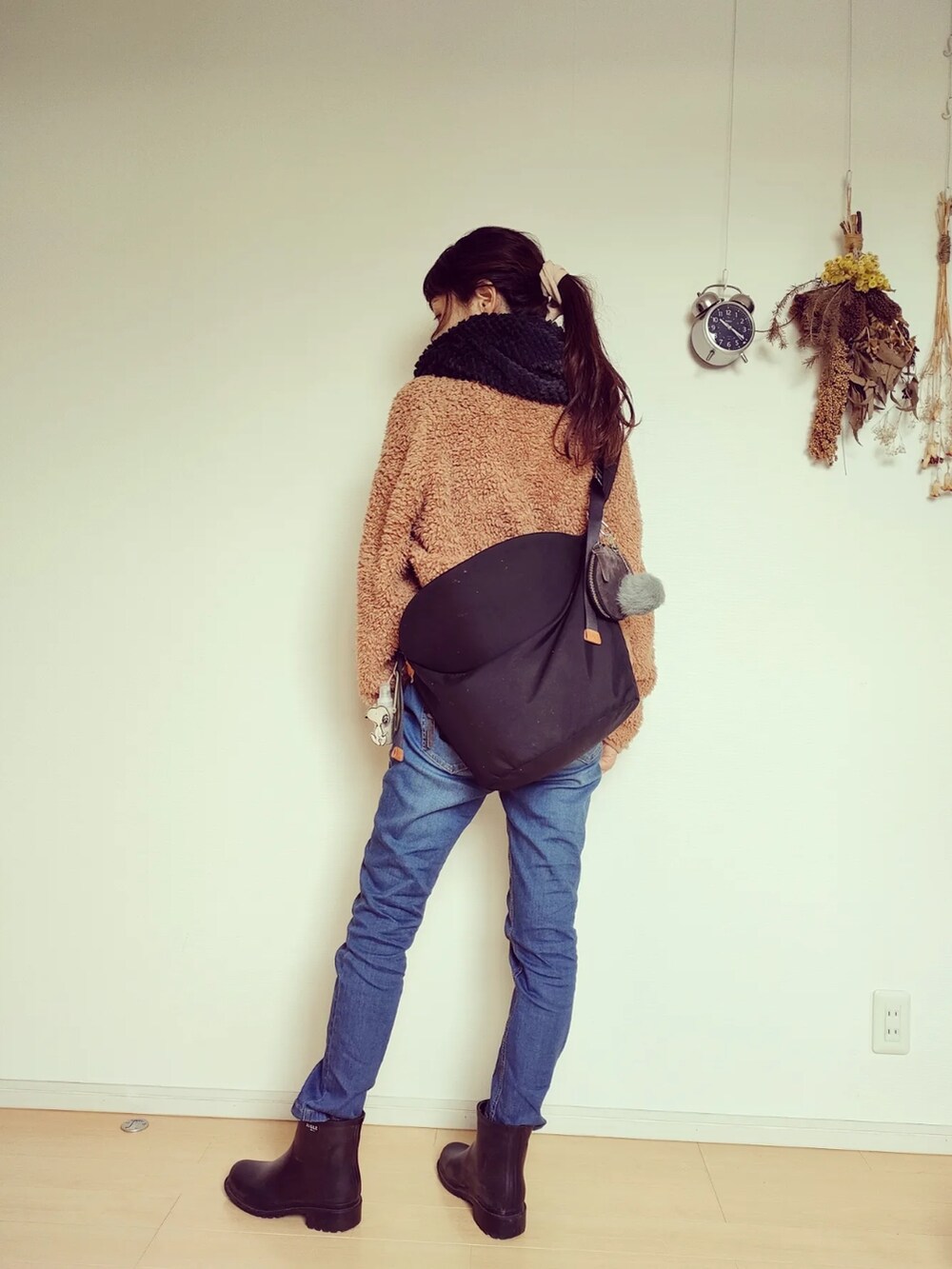 ブラック系のバッグ、ブラック系のレインシューズ、ブルー系のデニムパンツを着用したレディースの秋コーディネートの4枚目の写真