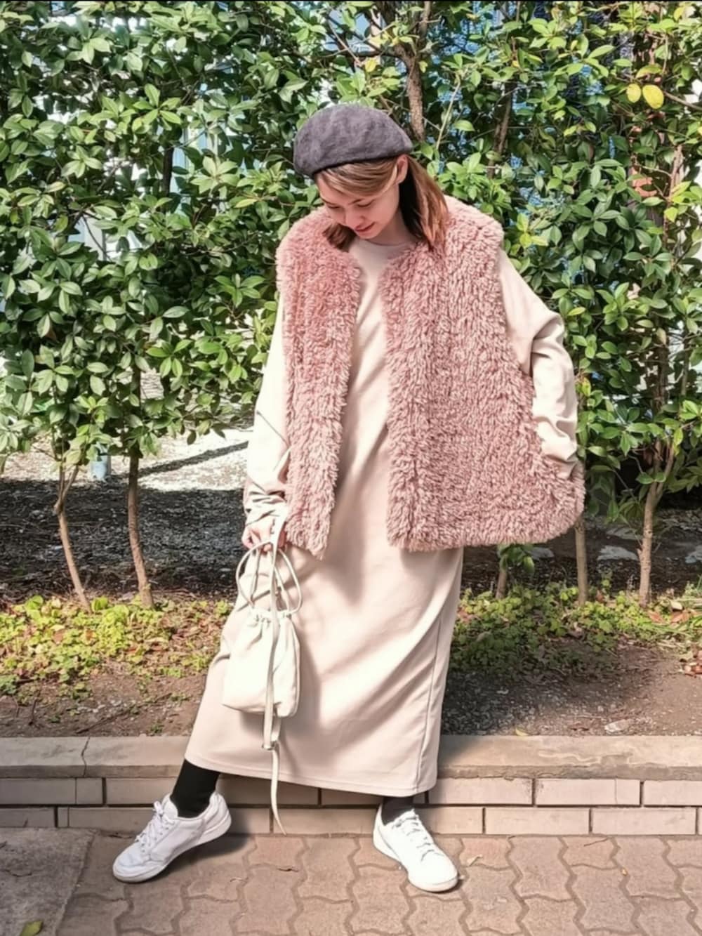 ベージュ系のワンピース、ブラック系のベスト、ホワイト系のショルダーバッグを着用したレディースの春コーディネートの2枚目の写真