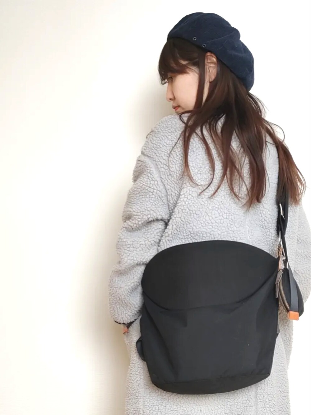 イエロー系のニット/セーター、ブルー系のその他アウター、ブラック系のバッグを着用したレディースの冬コーディネートの4枚目の写真