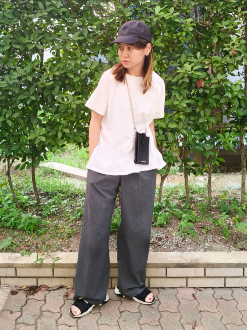ホワイト系のTシャツ/カットソー、ブラック系のショルダーバッグ、グレー系のパンツを着用したレディースの秋コーディネートの3枚目の写真