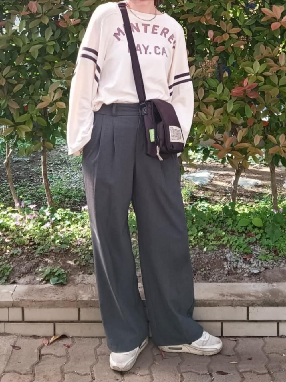 イエロー系のTシャツ/カットソー、ブラック系のショルダーバッグ、グレー系のパンツを着用したレディースの春コーディネートの2枚目の写真