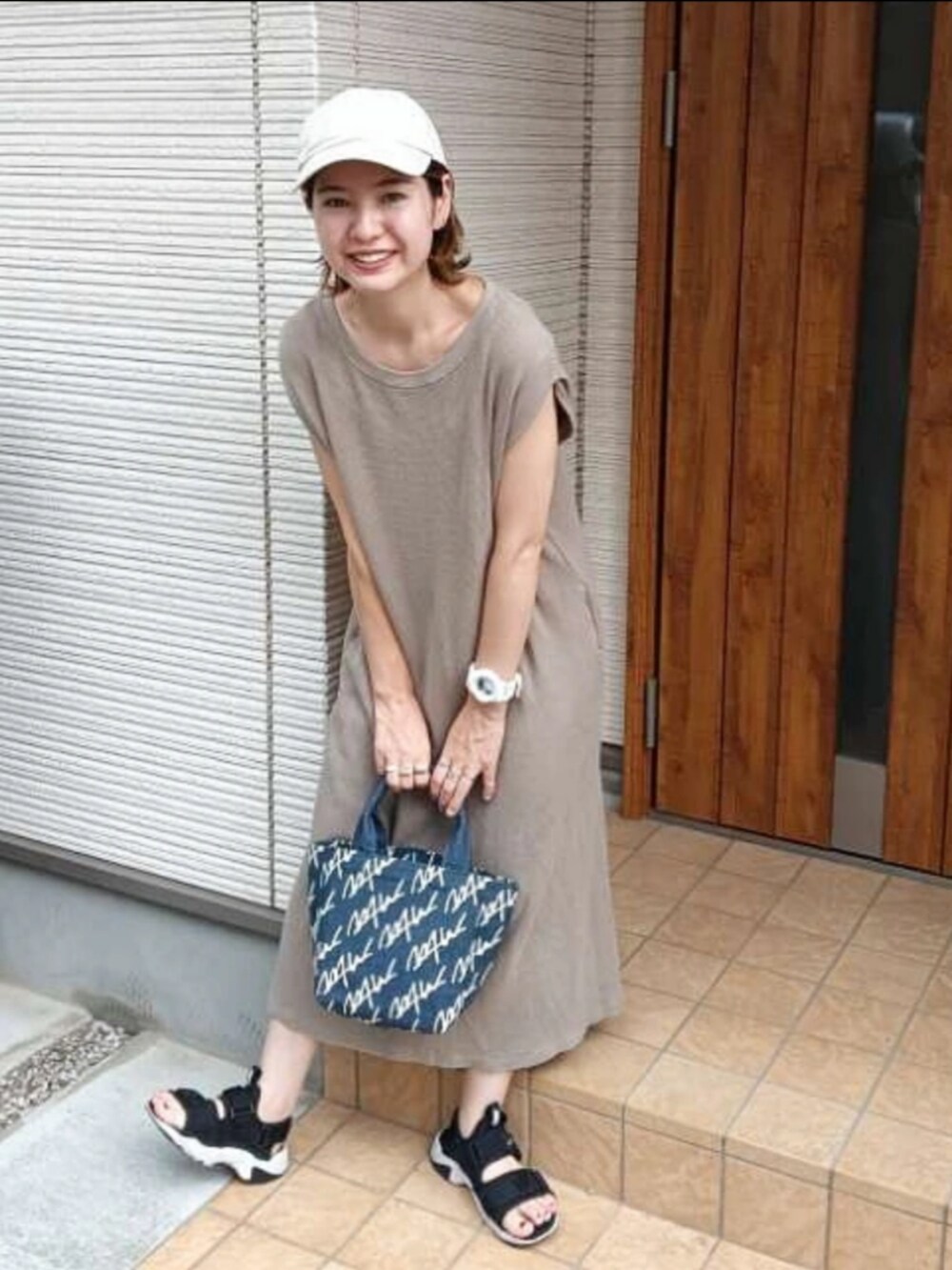 ブラウン系のワンピース、ブルー系のトートバッグ、ブラック系のサンダルを着用したレディースの夏コーディネートの3枚目の写真