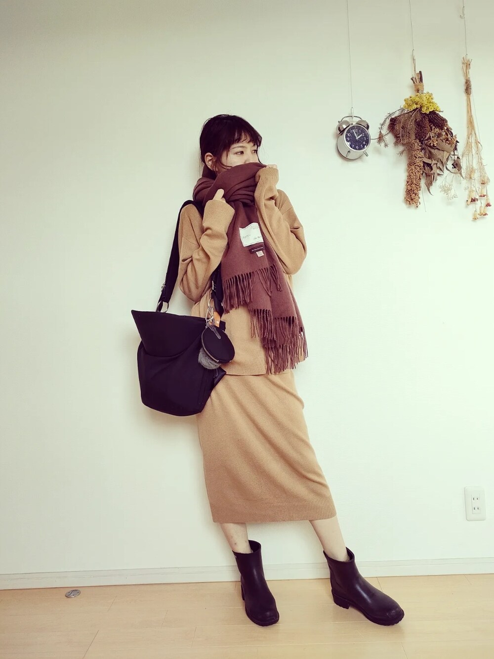 ブラック系のバッグ、ブラック系のレインシューズ、ベージュ系のセットアップを着用したレディースの秋コーディネートの2枚目の写真