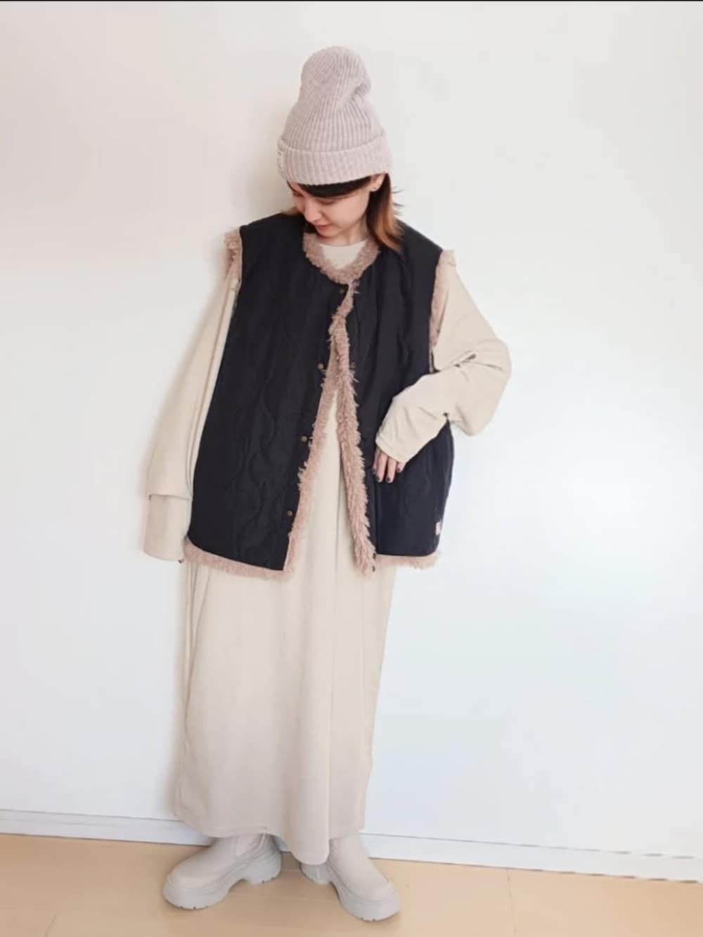 ブラック系のベスト、ベージュ系のワンピース、ベージュ系のブーツを着用したレディースの冬コーディネートの3枚目の写真