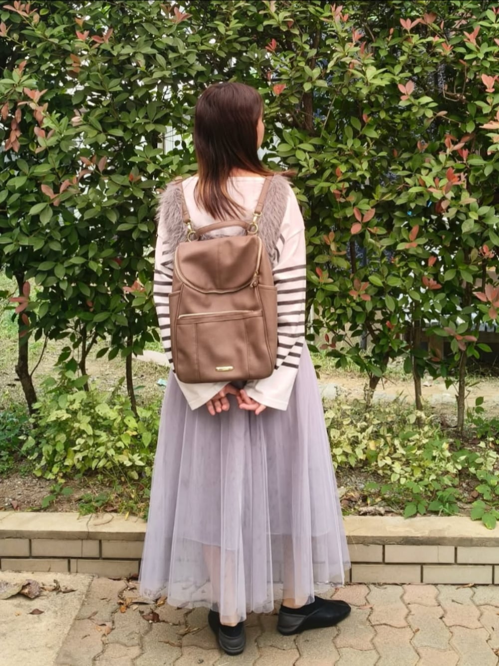 グレー系のベスト、ホワイト系のTシャツ/カットソー、グレー系のスカートを着用したレディースの秋コーディネートの3枚目の写真