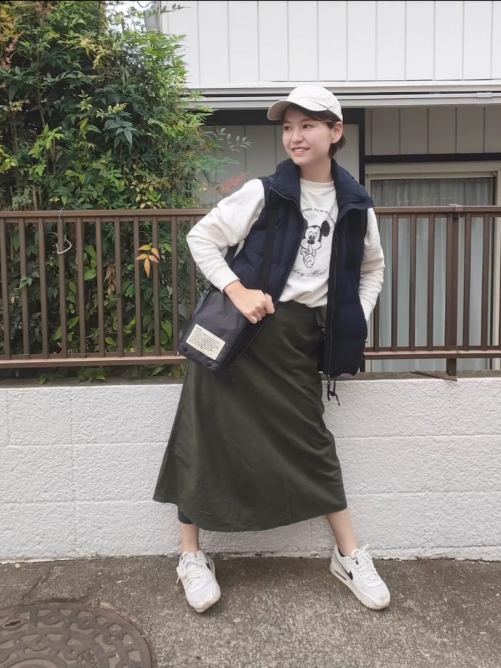 ブラック系のダウンベスト、ホワイト系のスウェット、ブラック系のショルダーバッグを着用したレディースの秋コーディネートの2枚目の写真