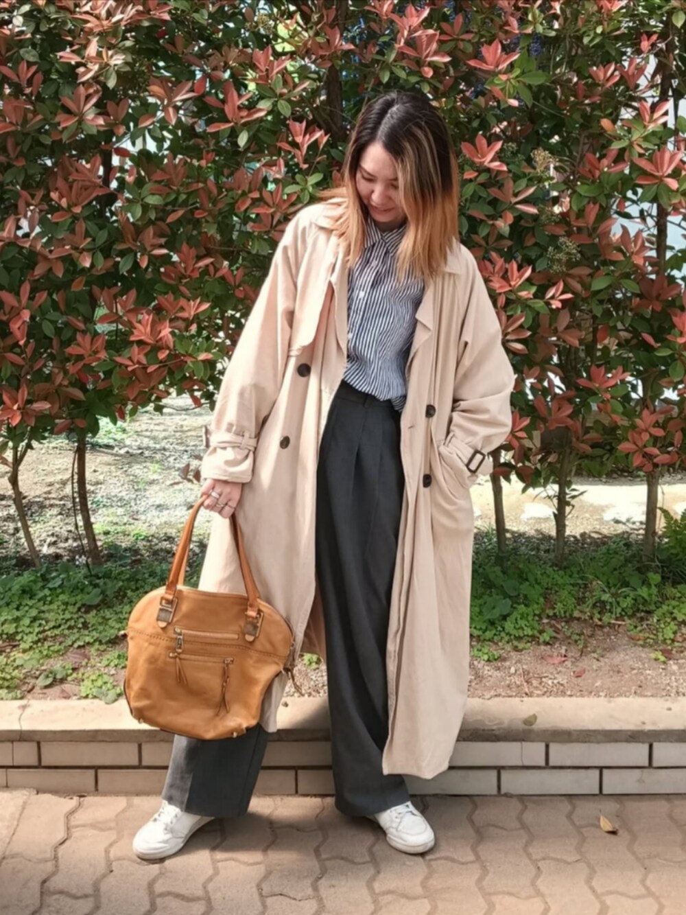 ブルー系のシャツ/ブラウス、ベージュ系のトレンチコート、ブラウン系のハンドバッグを着用したレディースの春コーディネートの3枚目の写真