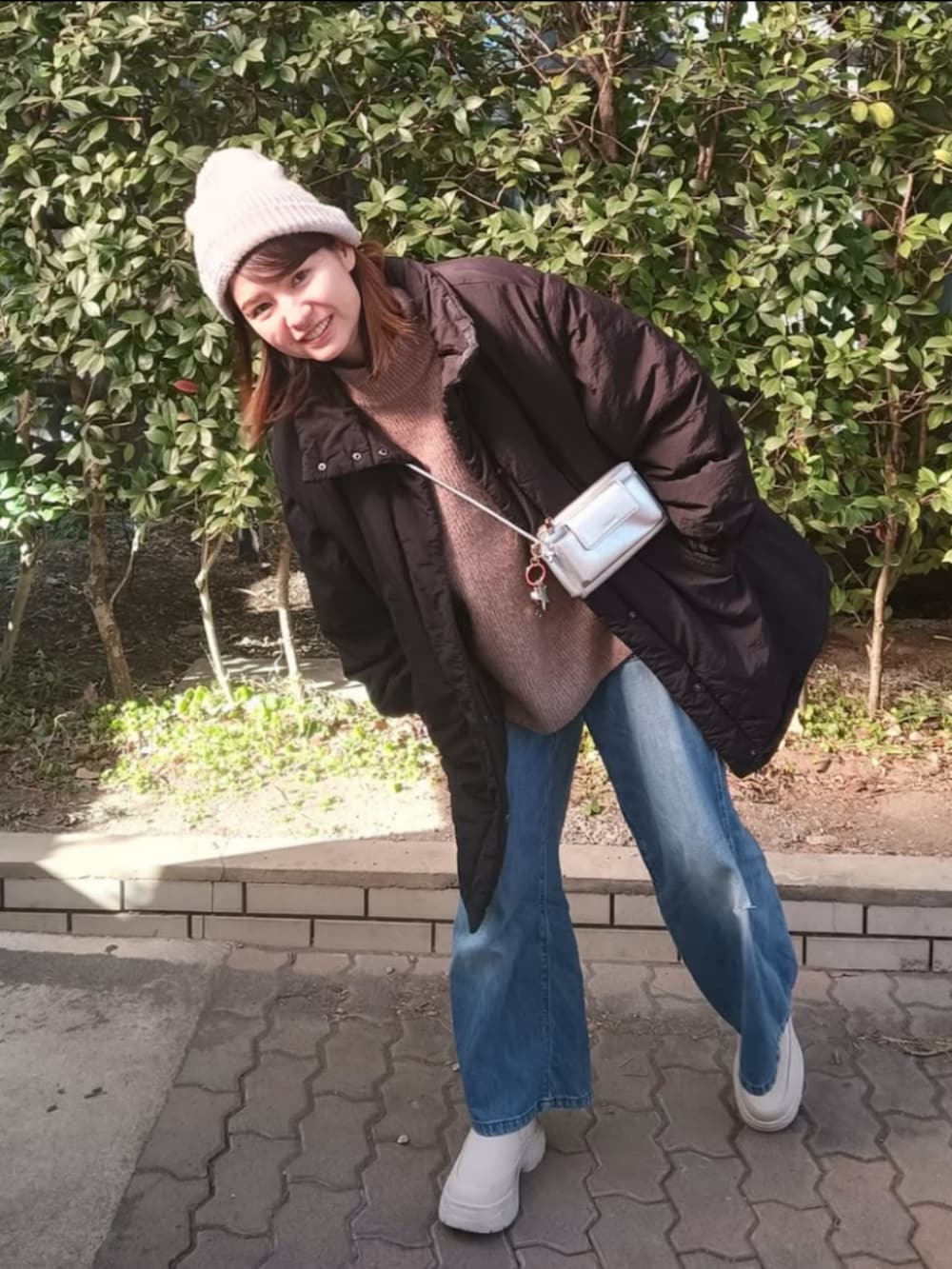 ブラック系のダウンジャケット/コート、ベージュ系のニット/セーター、ベージュ系のブーツを着用したレディースの冬コーディネートの3枚目の写真