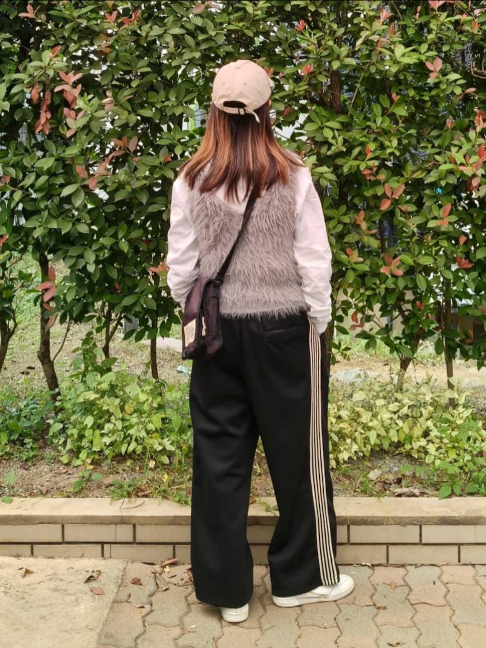 グレー系のTシャツ/カットソー、グレー系のベスト、ブラック系のショルダーバッグを着用したレディースの秋コーディネートの4枚目の写真