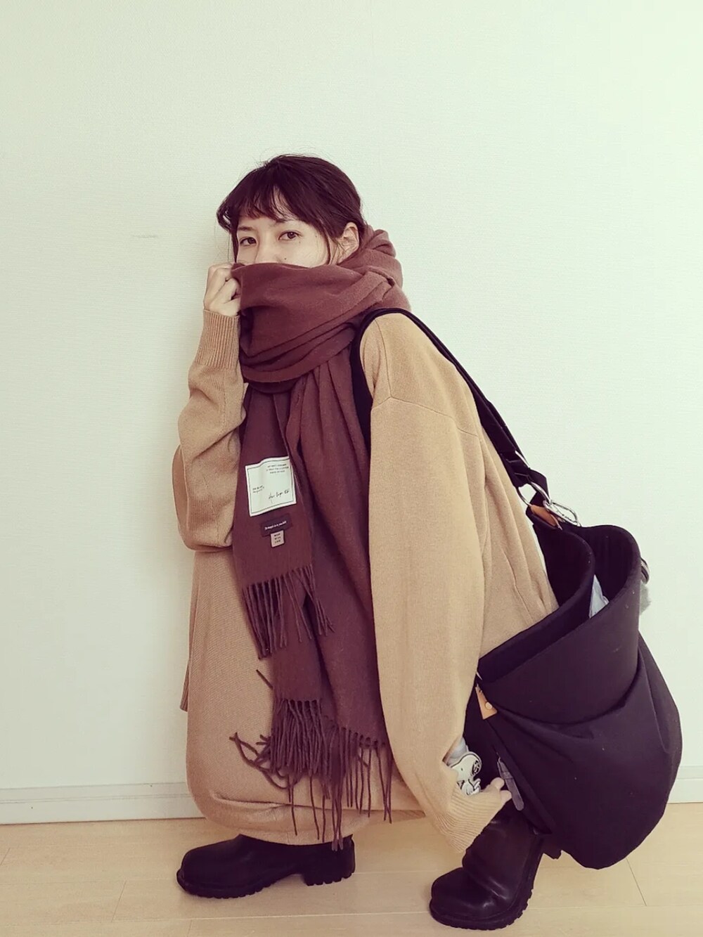 ブラック系のバッグ、ブラック系のレインシューズ、ベージュ系のセットアップを着用したレディースの秋コーディネートの3枚目の写真