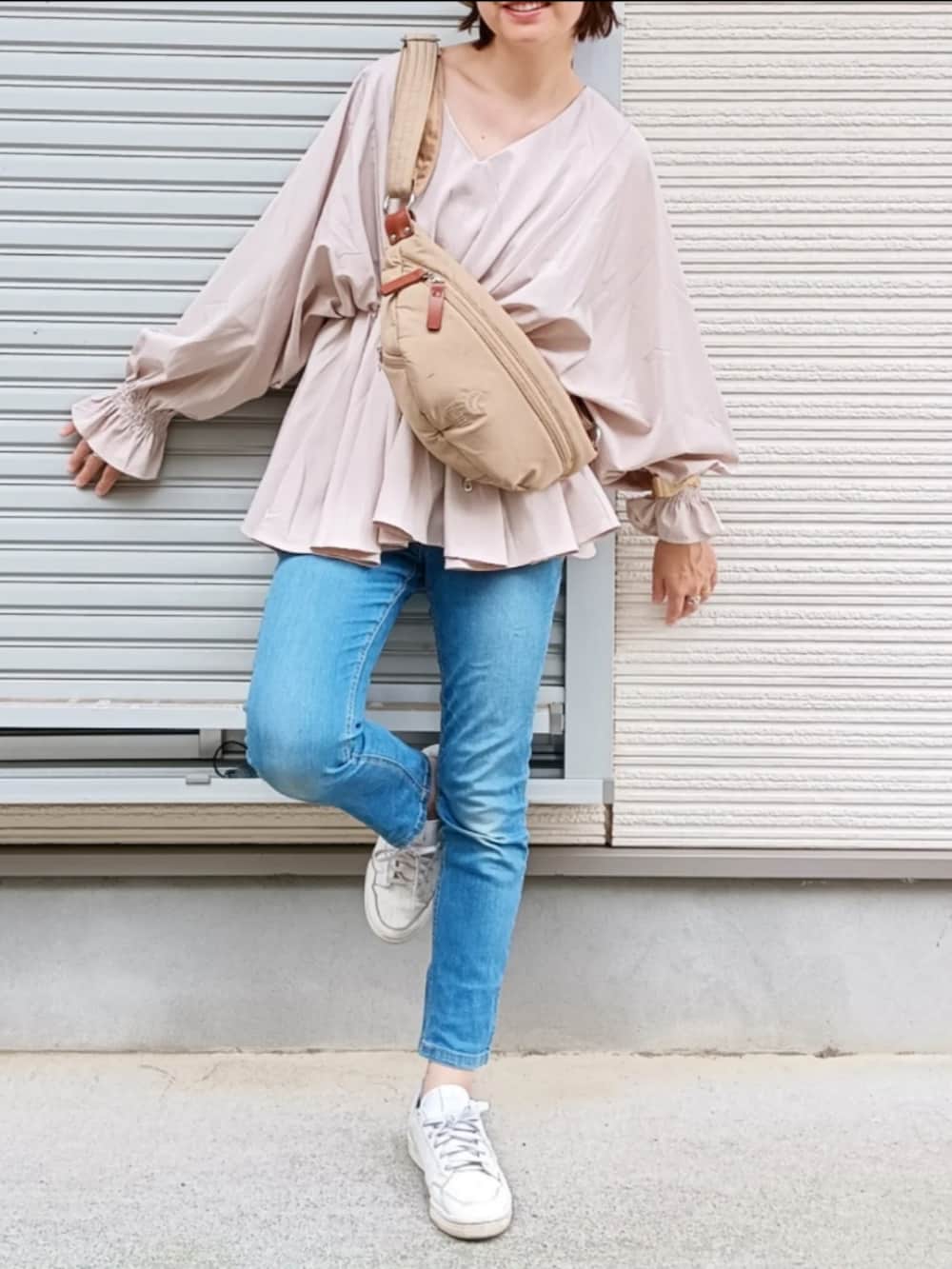 ベージュ系のショルダーバッグ、ブルー系のデニムパンツ、ホワイト系のスニーカーを着用したレディースの夏コーディネートの2枚目の写真