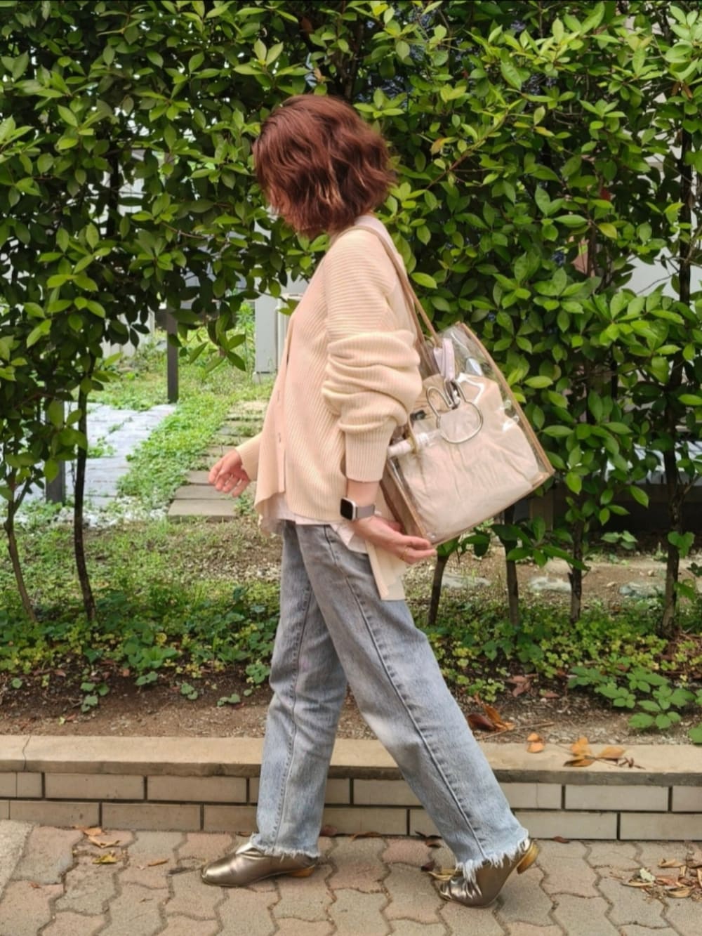 ホワイト系のカーディガン/ボレロ、ブルー系のデニムパンツ、ゴールド系のパンプスを着用したレディースの秋コーディネートの2枚目の写真