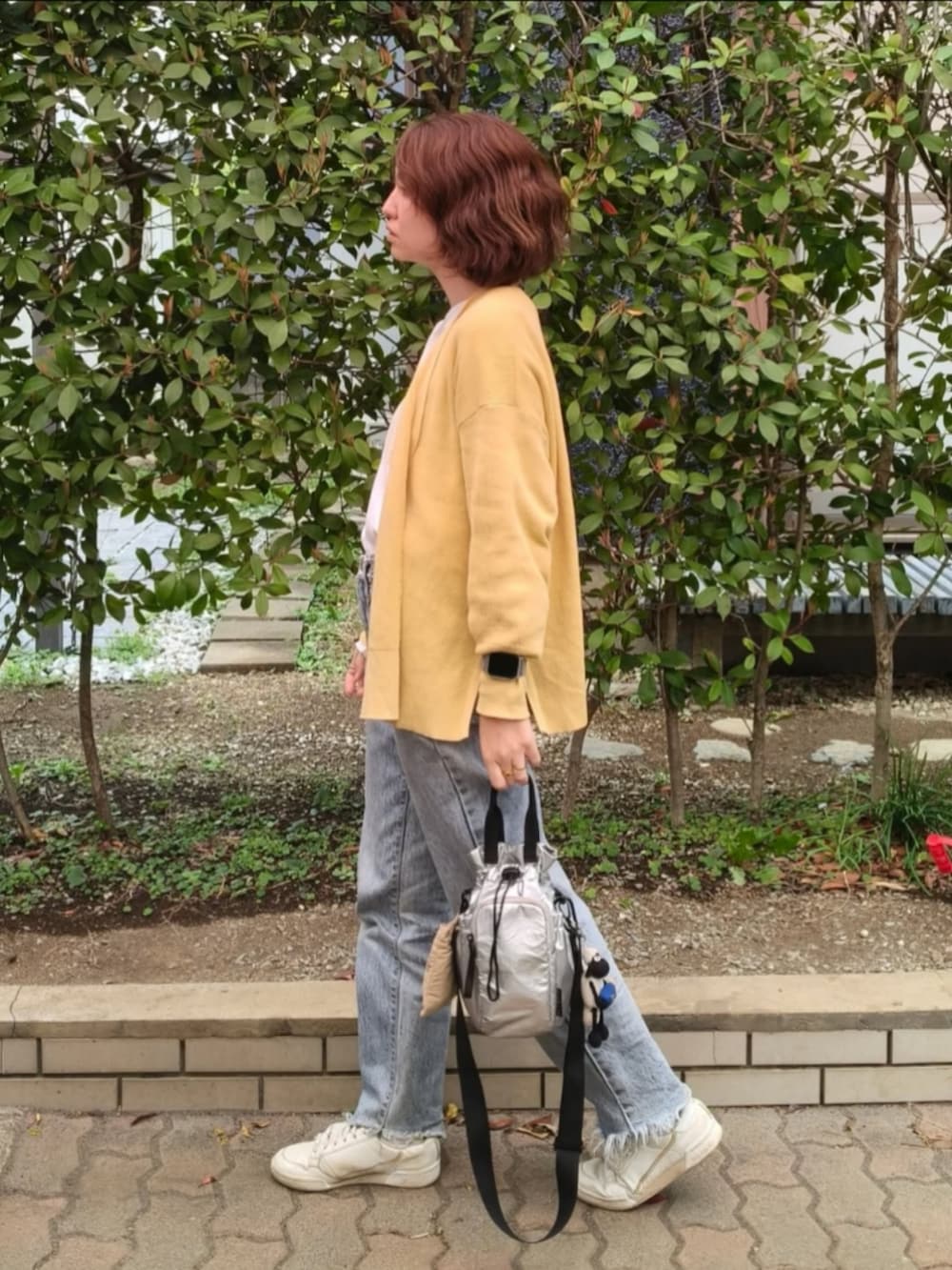 グレー系のTシャツ/カットソー、グリーン系のカーディガン/ボレロ、ブルー系のデニムパンツを着用したレディースの春コーディネートの2枚目の写真